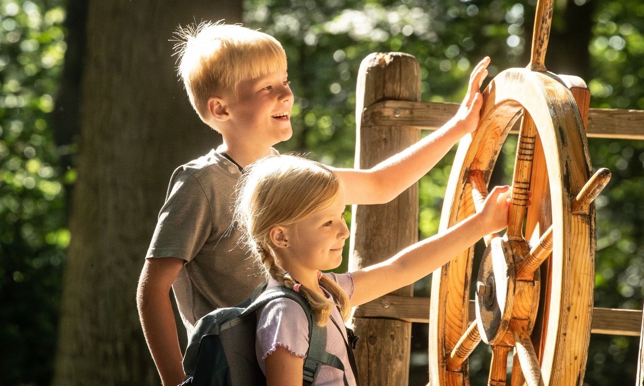 Junge und Mädchen drehen an einem Rad im Tierpark Ströhen