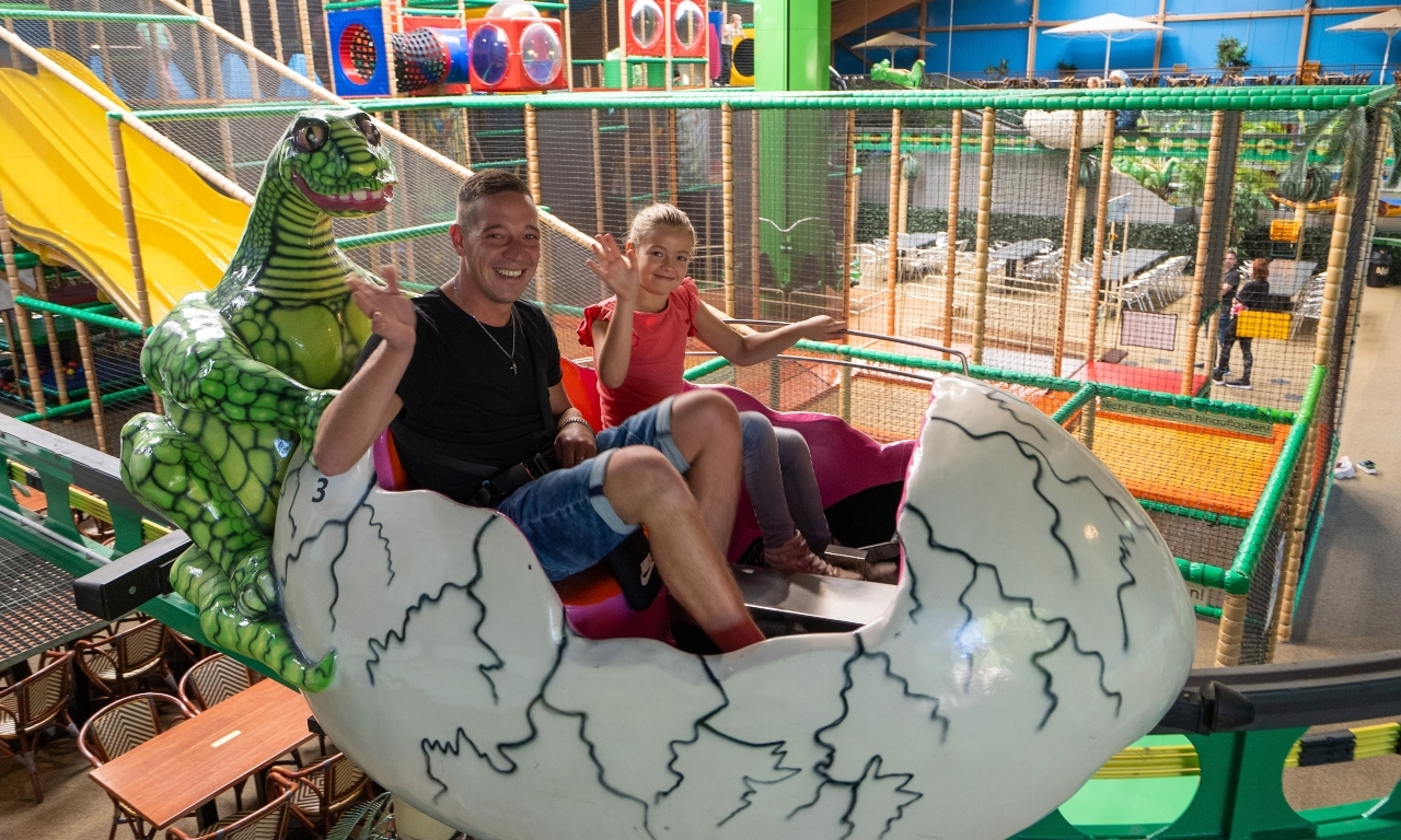 Vater und Tochter sitzen in einer Dinoei-Achterbahn bei Kids Dinoworld